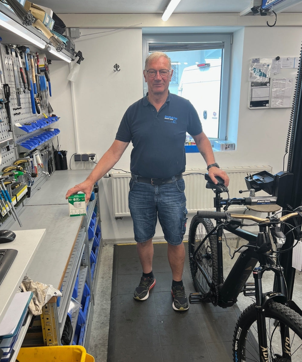 Fahrradhändler lädt E-Bike mit dem Akku Life Guard in der Werkstatt – optimale Akku-Pflege für Kundenräder und Leihbikes