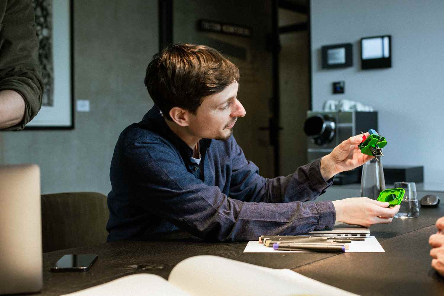 Entwickler von Natune zeigt Akku Life Guard in Nahaufnahme, Fokus auf Produkt und Gespräch